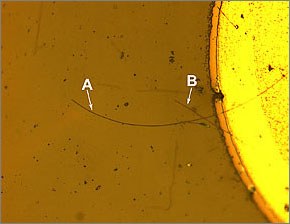 Micrograph of a complete nanowire LED. The long nanowire (A) is about 110 micrometers long, a shorter nanowire (B) crosses it. The circular section is the metal post from which the nanowires are aligned.